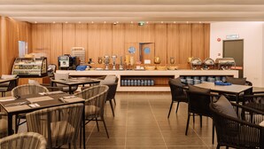 A modern cafe with wooden panel walls, a counter with various food items, and multiple seating arrangements. - Impiana by Roxy Hotel  (Kuching)