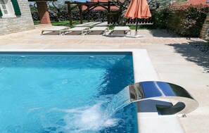 A swimming pool with clear blue water, surrounded by a stone deck and lounge chairs. - Beautiful home in Porec (Porec)
