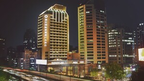 Um hotel alto com fachada em linhas retas e sinalização iluminada.