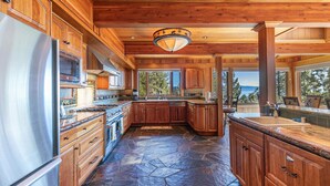 A spacious kitchen with wooden cabinets, a large island, and a stone floor.