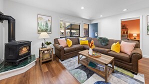 A modern living room with a black wood-burning stove, a brown leather sofa, and a wooden coffee table.