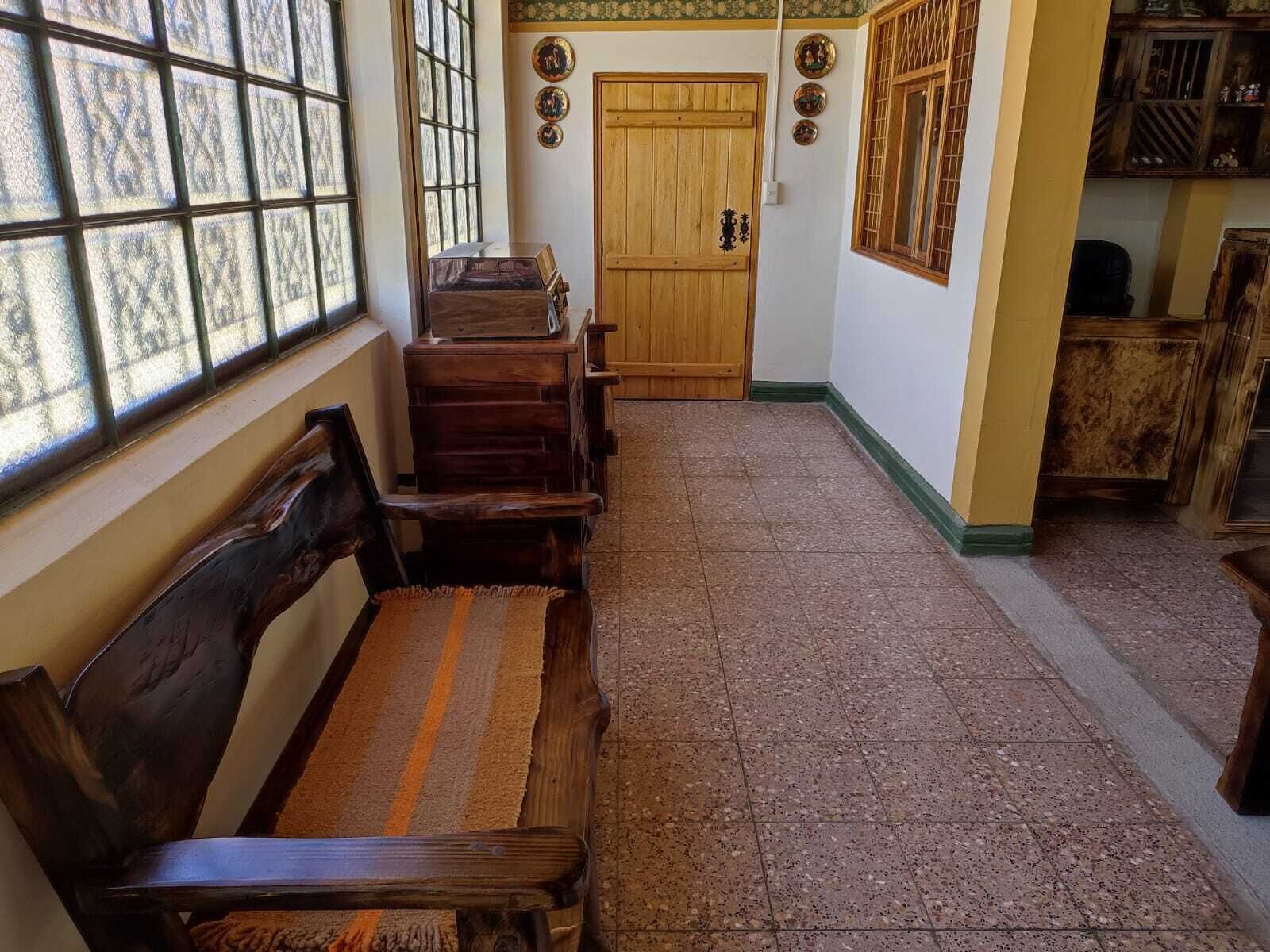Un pasillo con bancos de madera, una puerta de madera y piso de baldosas.