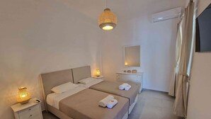 Habitación de hotel con dos camas, una mesita de noche con lámpara, cómoda, espejo y cortina.
