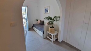 Un dormitorio con cama, una mesita de noche con planta, armario y puerta que da a un balcón.