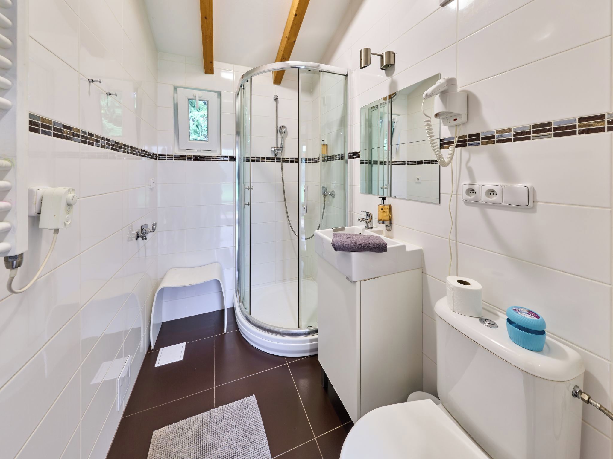 Een moderne badkamer met een douchecabine van glas, een toilet, een wastafel en een spiegel.