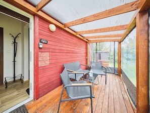 Un espace extérieur aménagé, abrité et doté d’un plancher en bois et de murs rouges.
