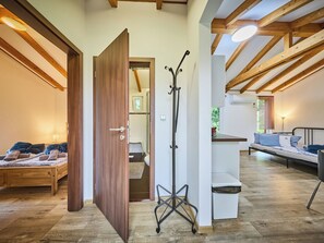 Une pièce spacieuse avec un plancher en bois, un lit avec des serviettes, un porte-manteau et un canapé.