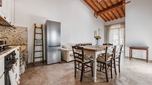 A compact kitchen with a built-in refrigerator, a wooden dining table with chairs, and a small side table. - Wonderful private villa with WIFI, A/C, private pool, TV and pets allowed, close to San Gimignano (Colle Di Val D’elsa)