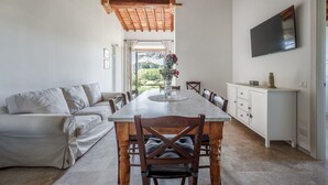 A modern kitchen with a dining table, wooden chairs, a sofa, and a TV mounted on the wall. - Wonderful private villa with WIFI, A/C, private pool, TV and pets allowed, close to San Gimignano (Colle Di Val D’elsa)
