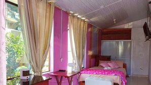 Een slaapkamer met een bed, nachtkastje en een klein bureau.