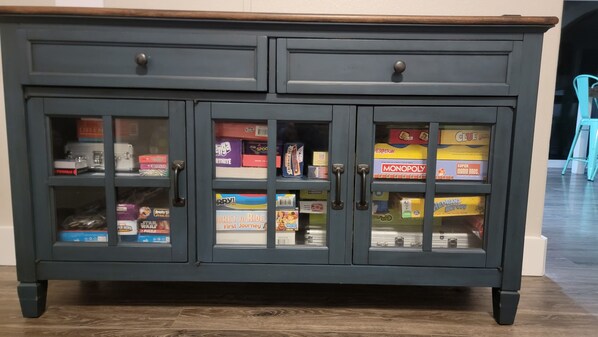 A dark blue cabinet with glass doors, containing various board games and puzzles.