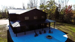 A large barn with a covered patio area, outdoor seating, and a fire pit.