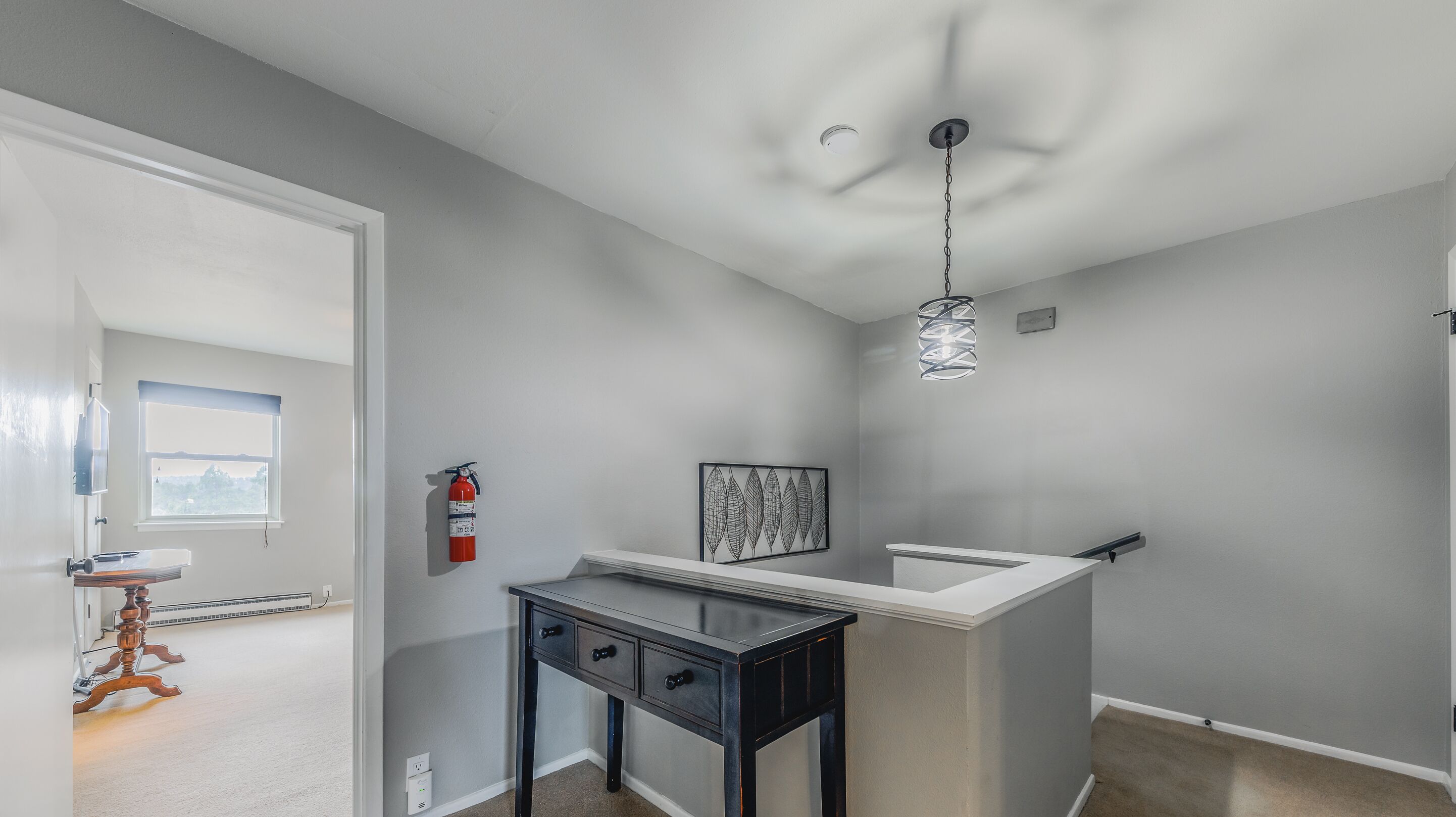A modern bathroom with a white vanity, a black console table, and a ceiling light fixture.