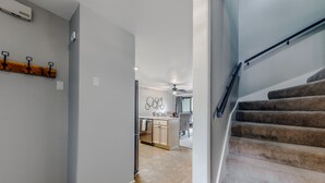 A modern kitchen with a central island, a dining area with chairs, and a staircase with carpeted steps. - On Mountain Time | Upscale Townhome Retreat w/ Cozy Nights & Outdoor Adventure Nearby (Alto)