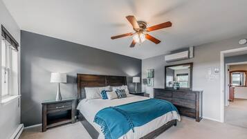 A bedroom with a bed, two bedside tables, a ceiling fan, a dresser, and a mirror.