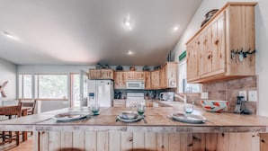 A spacious kitchen with wooden cabinets, a central island with dining setup, and a view to the outside.