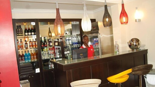 Zona de bar con un cantinero, una variedad de botellas de licor y lámparas colgantes de diseño.