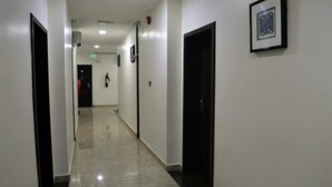 Un pasillo con puertas a ambos lados, suelo de baldosas y un cuadro enmarcado en la pared.