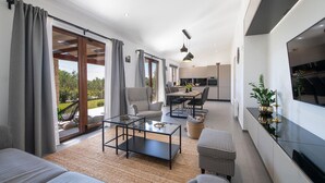 Uma sala de estar moderna com um sofá, mesa de centro e área de jantar com cadeiras e mesa.