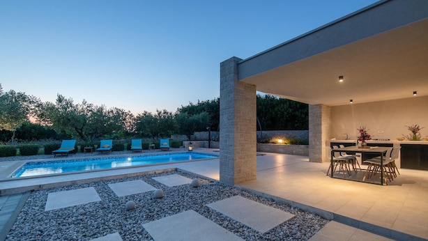 Uma área de piscina moderna ao ar livre, com espaço de refeições e espreguiçadeiras.
