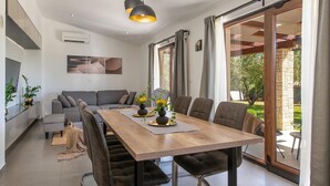 Um espaço de estar moderno com área de jantar, sofá e vista para o exterior.