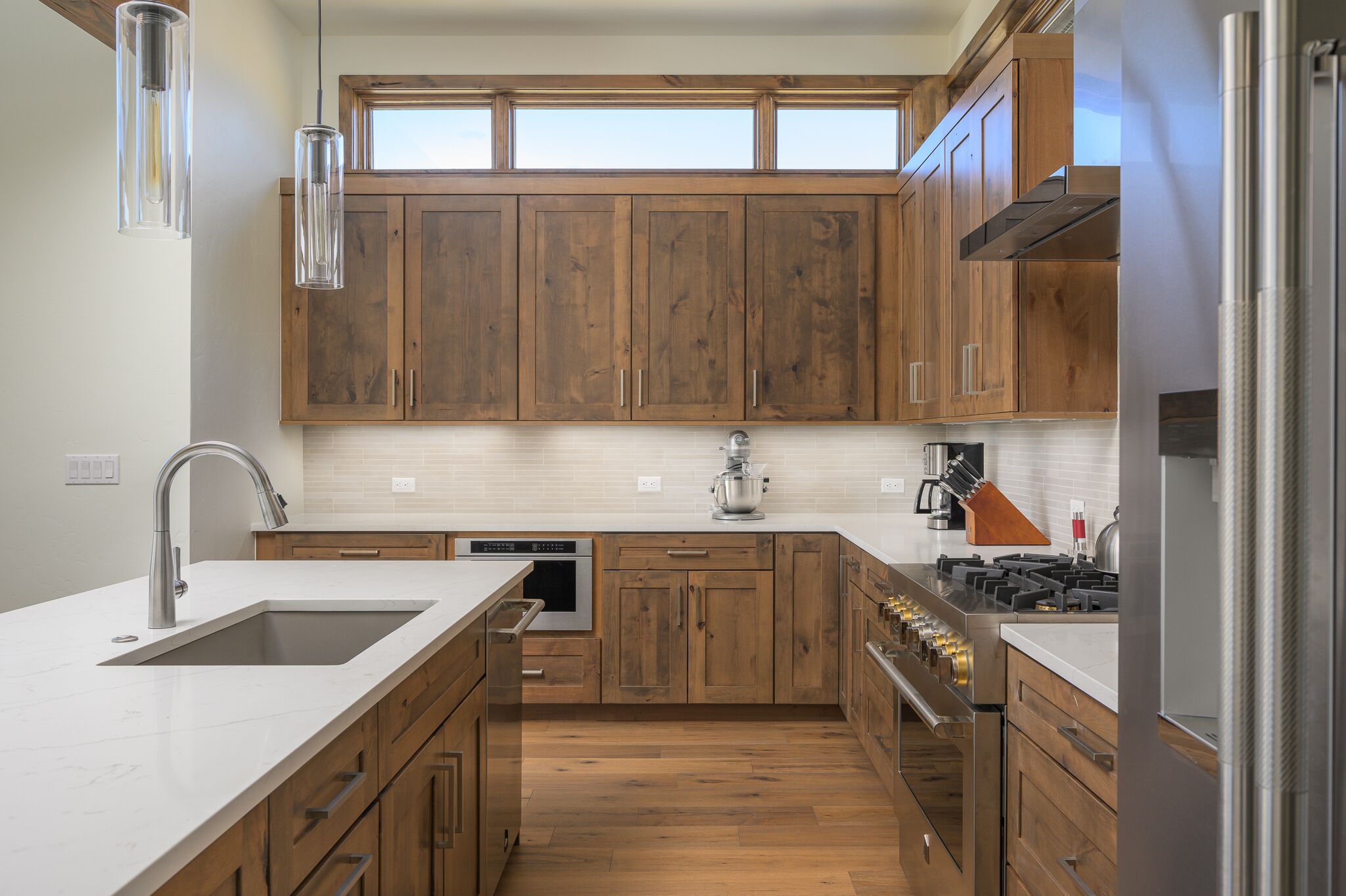 A modern kitchen with wooden cabinets, a stainless steel sink, and a built-in oven.