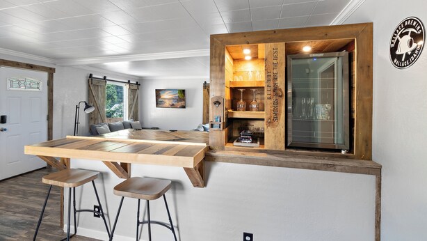 Une cuisine moderne dotée d’un îlot central en bois, de tabourets de bar et d’une cave à vin intégrée.