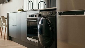 Une cuisine moderne équipée d’appareils électroménagers en acier inoxydable, notamment un four à micro-ondes, un four et un lave-linge.