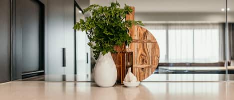 A kitchen counter with a white vase, a wooden bowl, and a potted plant.