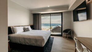 Une chambre d’hôtel moderne avec un grand lit, un bureau et une vue sur la mer.