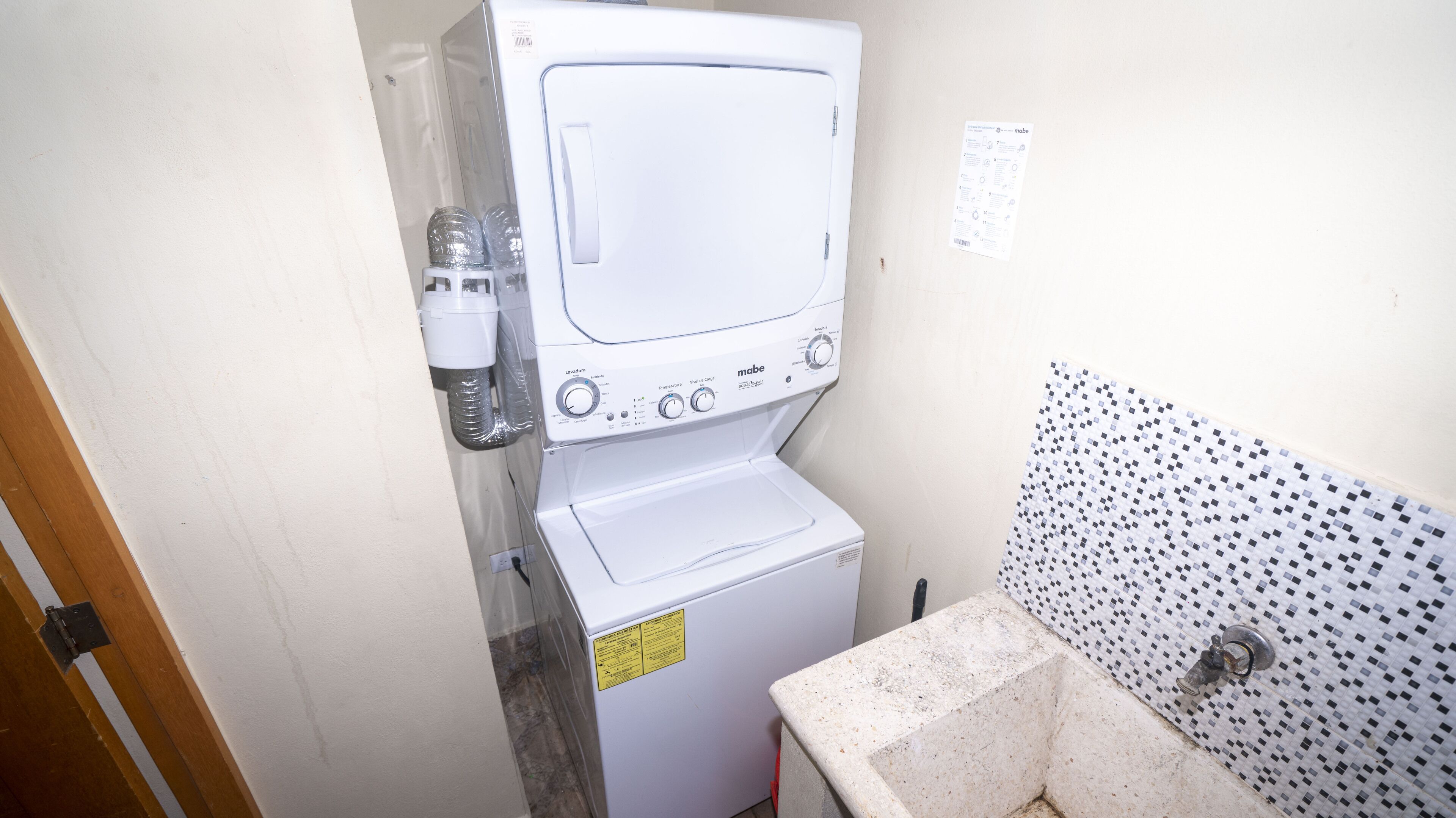 A compact laundry room with a front-loading washing machine and a stacked dryer.