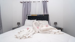 Ein ordentlich bezogenes Bett mit weißen Leinen, eine Handtuch-Herz-Drapierung und zwei Nachttische mit Lampen.