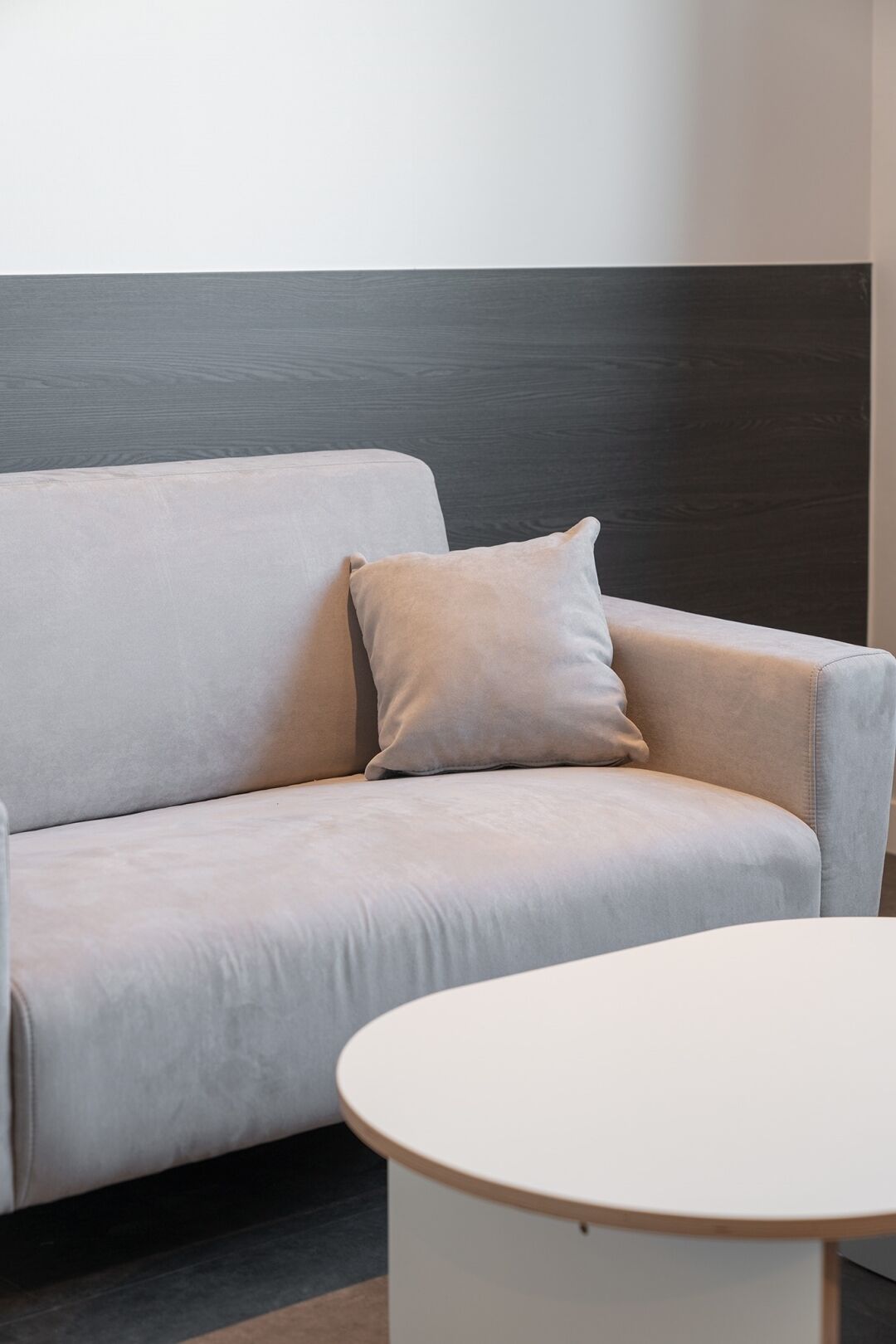 A modern, minimalist room with a light-colored sofa and a round white table.