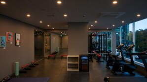 Une salle de sport équipée de matériel d’exercice, d’un tapis de course et d’un distributeur d’eau.