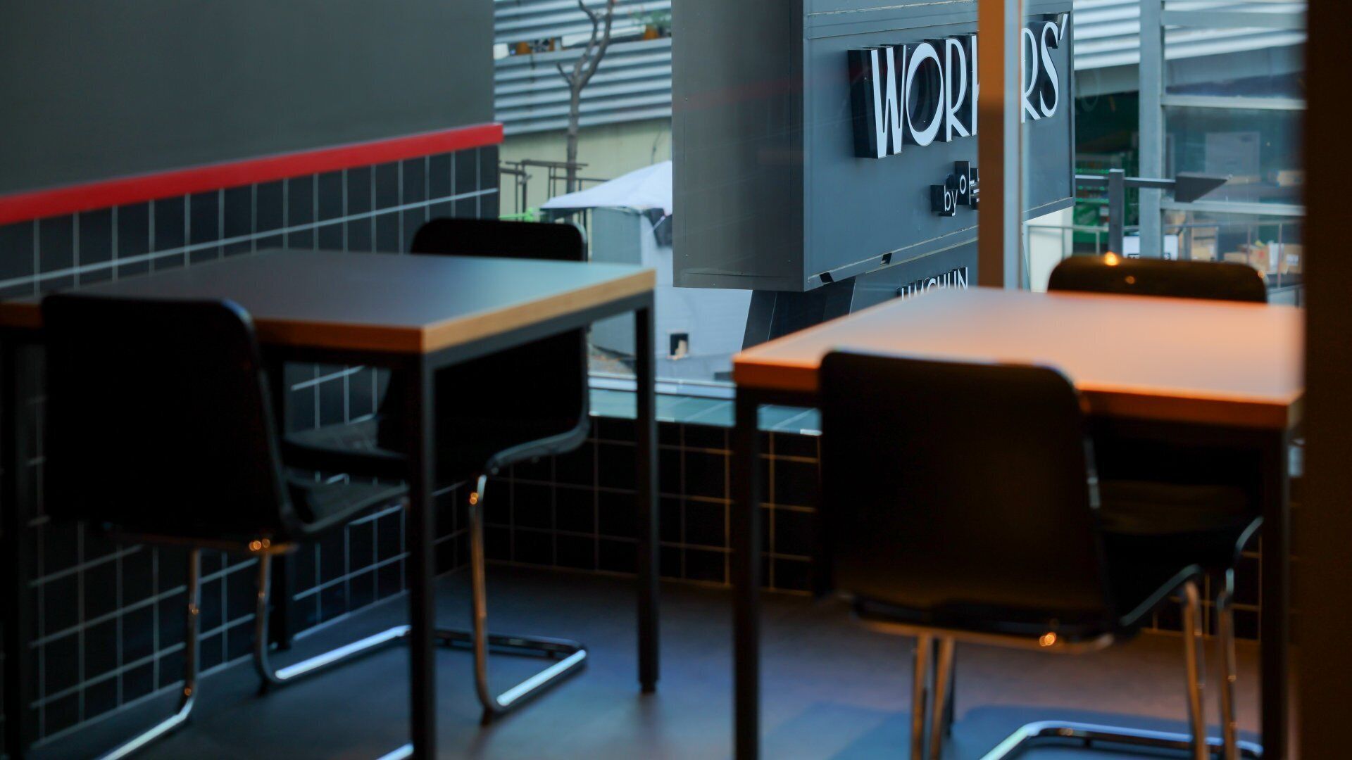 A modern interior with a dining area featuring a table and chairs, a grey wall with a red stripe, and a window with blinds.