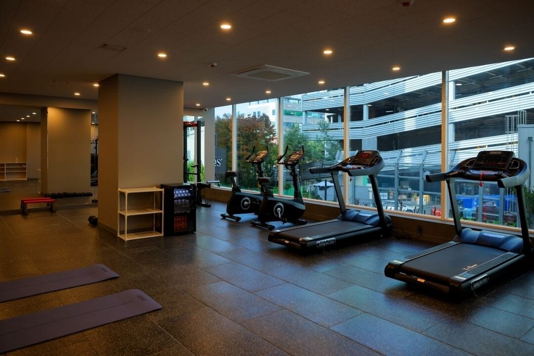 A gym with treadmills, stationary bikes, and a bench.