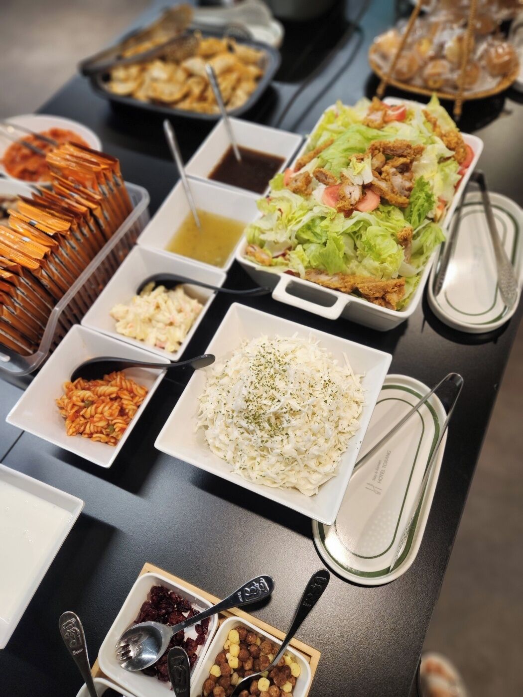 A buffet table with various dishes including pasta, salad, and rice.