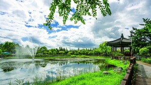 Un parc paisible avec un étang, un kiosque et une fontaine.