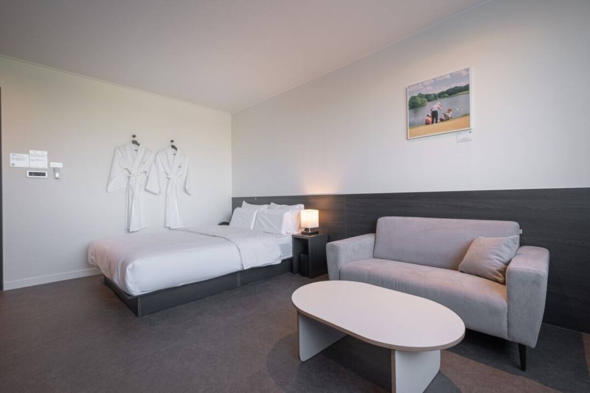Une chambre d’hôtel avec deux lits, un canapé, une table et un tableau au mur.