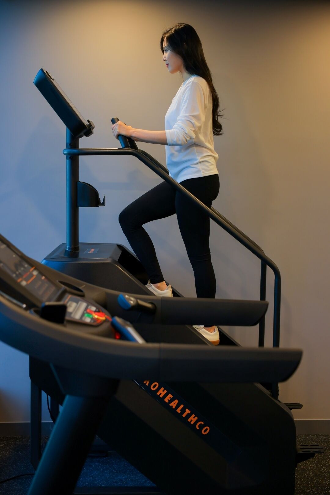 A woman using a treadmill in a gym with a control panel and a digital display.