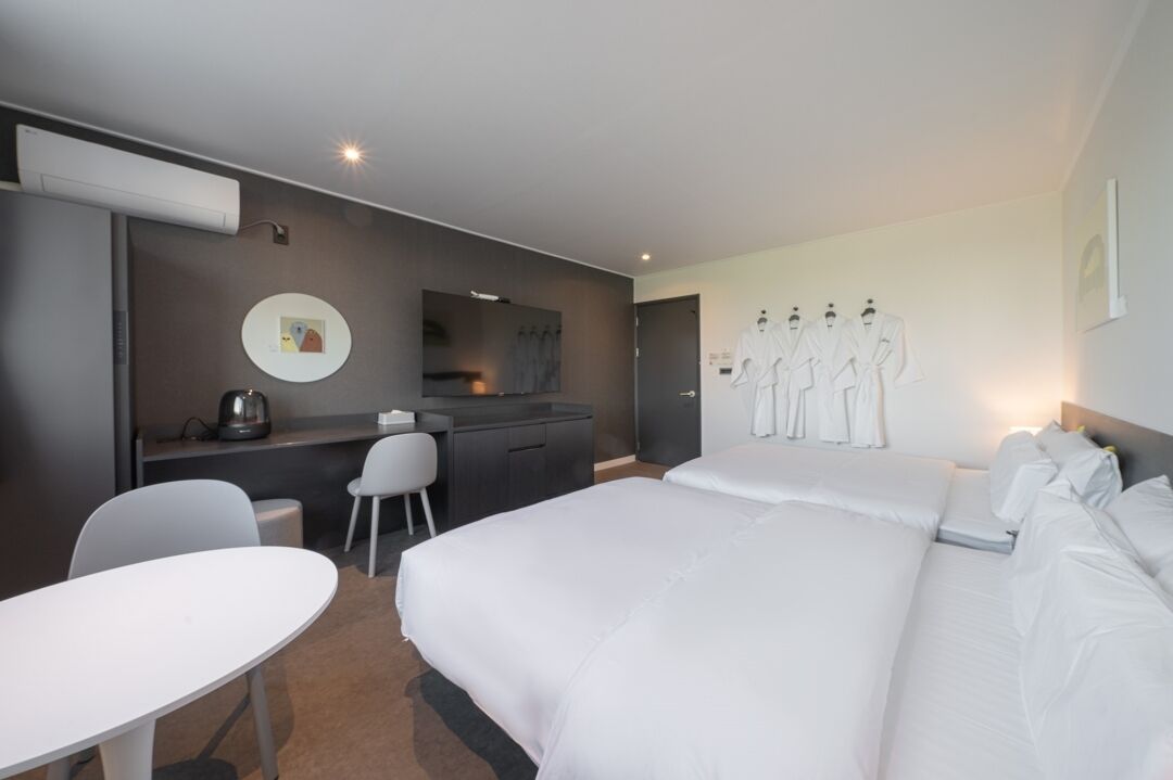 A hotel room with a bed, a desk, a chair, and a small table.