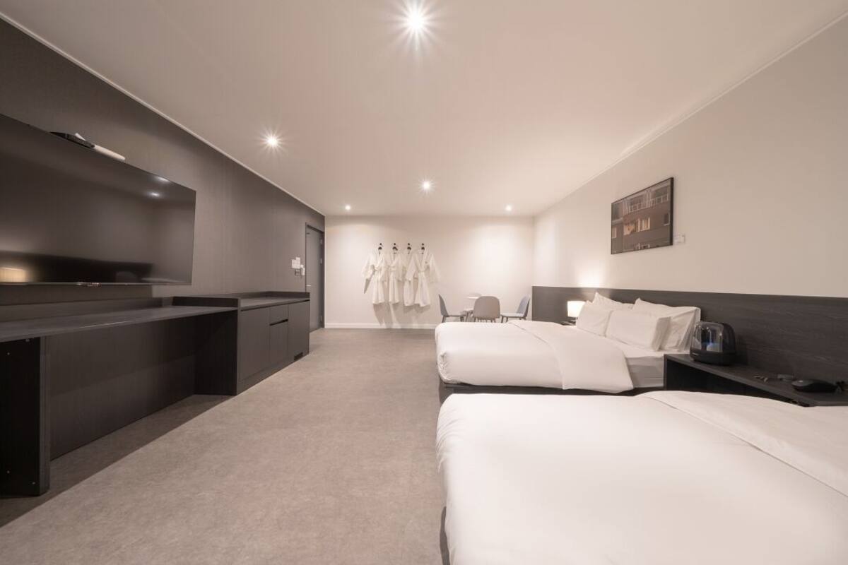 Une chambre d’hôtel moderne avec deux lits, un bureau et un coin salon.