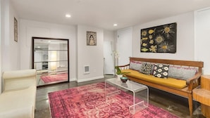 Een moderne woonkamer met een bank, een bijzettafeltje en een rood tapijt met een patroon.