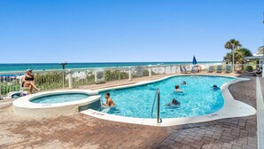A swimming pool with a view of the ocean, surrounded by lounge chairs and a brick patio. - Seychelles 703 | Beach Chair Service Included at this 7th Floor, Oceanfront Condo (Panama City Beach)