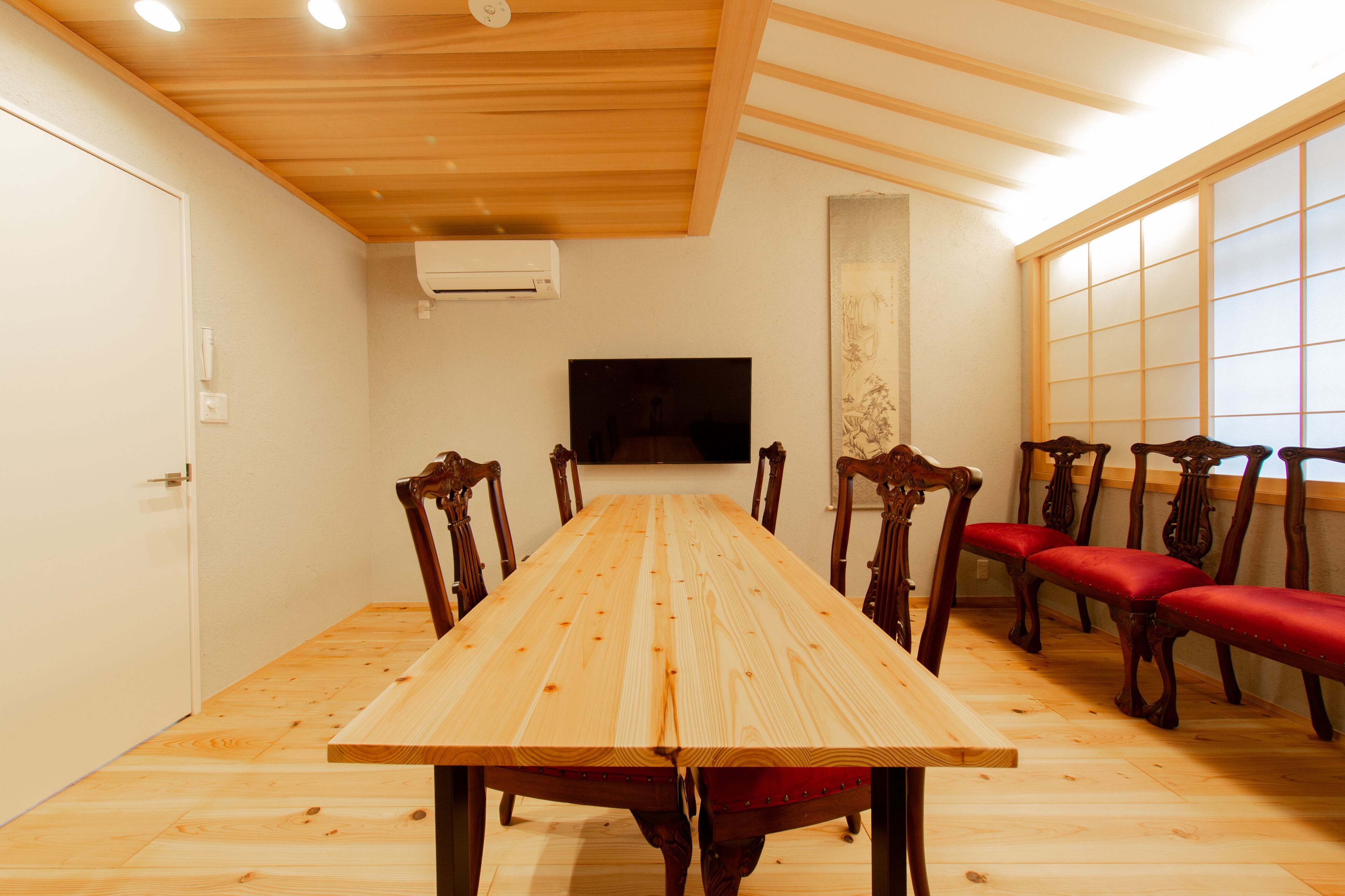 Comedor con una larga mesa de madera, seis sillas, un televisor y un ventanal corredero.