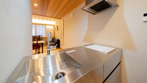 Een moderne keuken met een roestvrijstalen spoelbak, houten plafond en een inbouwafzuigkap.