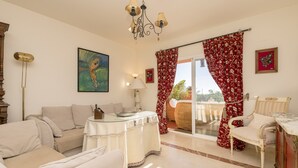 Ein geräumiges Wohnzimmer mit einer Couch, einem Esstisch und einem Balkon mit roten Vorhängen.