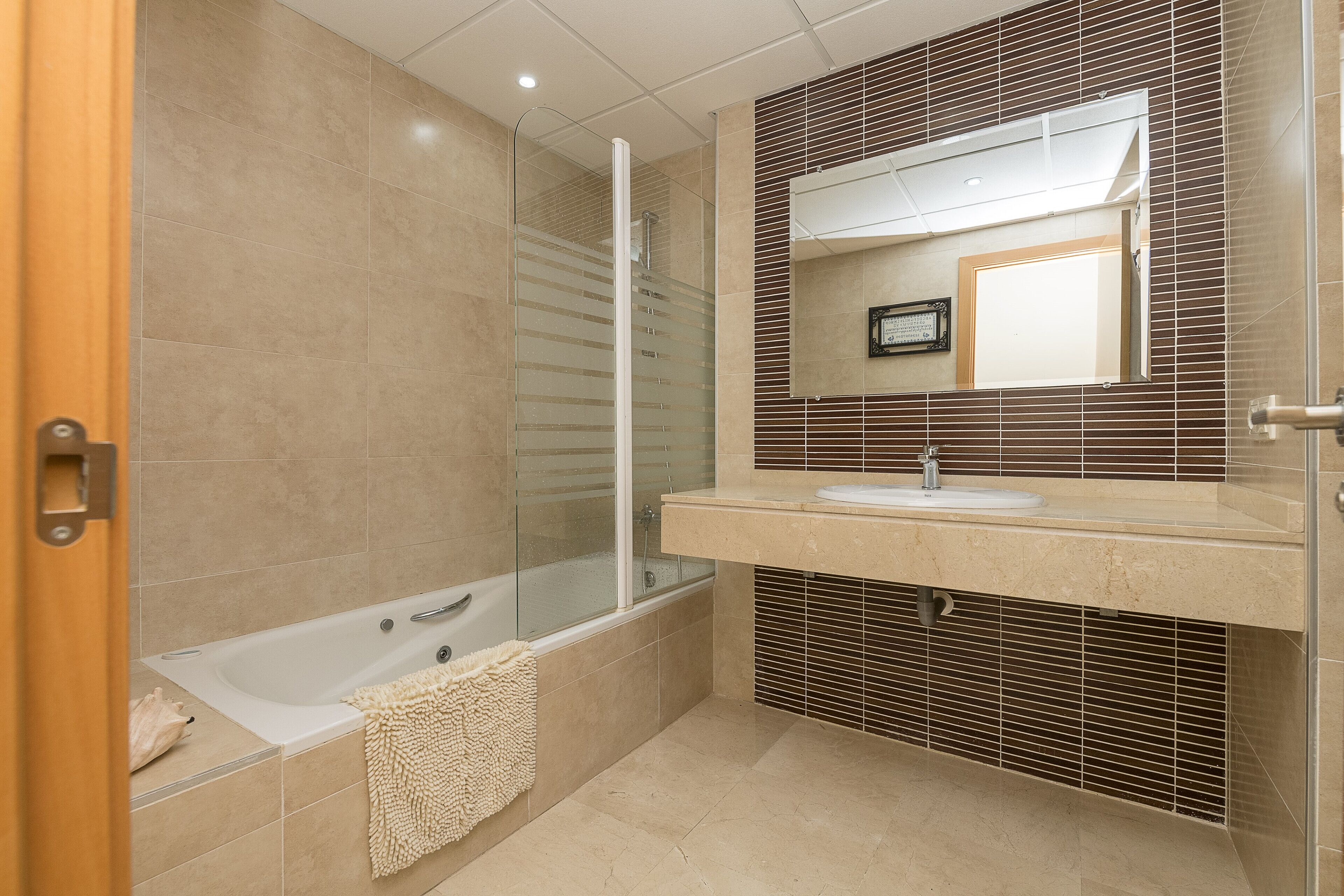 Un baño moderno con ducha de vidrio, bañera y tocador con lavamanos.