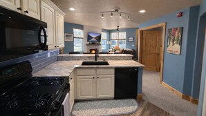 A kitchen with white cabinets, a black stove, and a marble countertop. - 5 minute walk to shops! Great Location and private garage (Park City)
