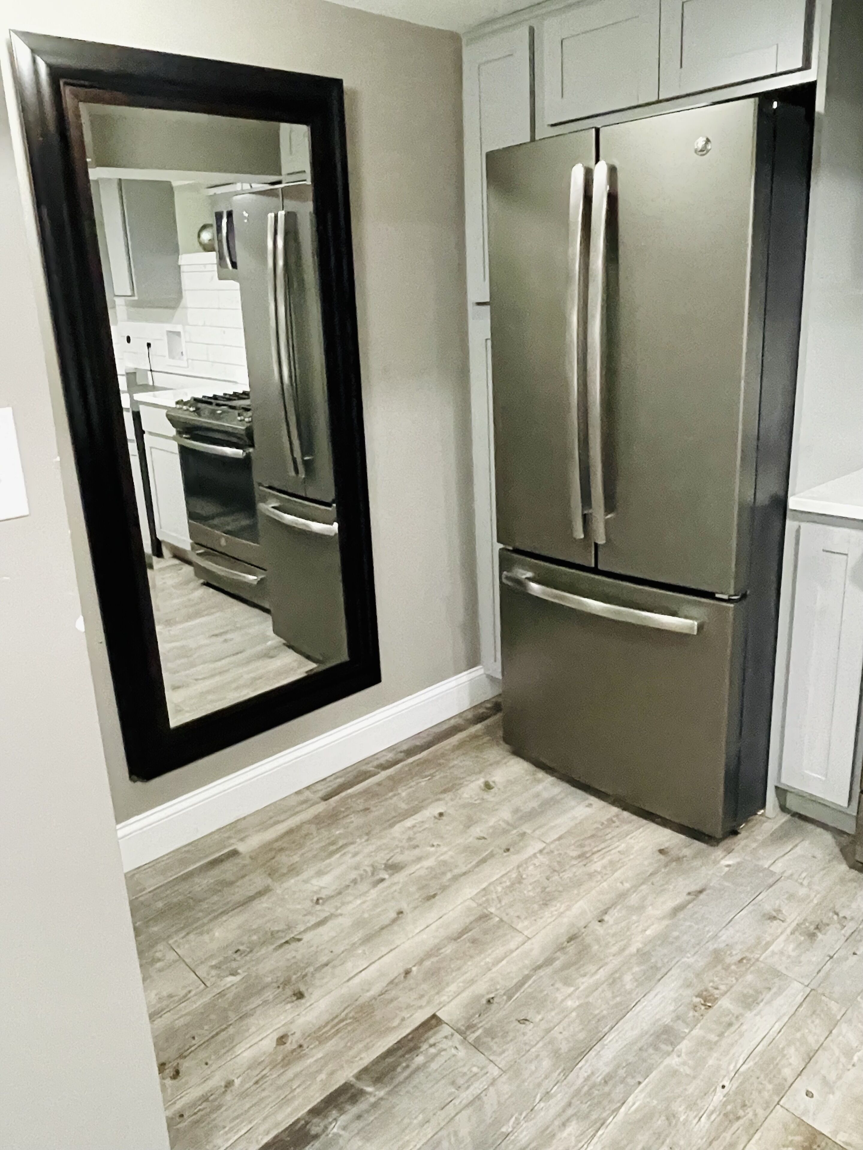 A kitchen with a stainless steel refrigerator, a double oven, and a wooden floor.